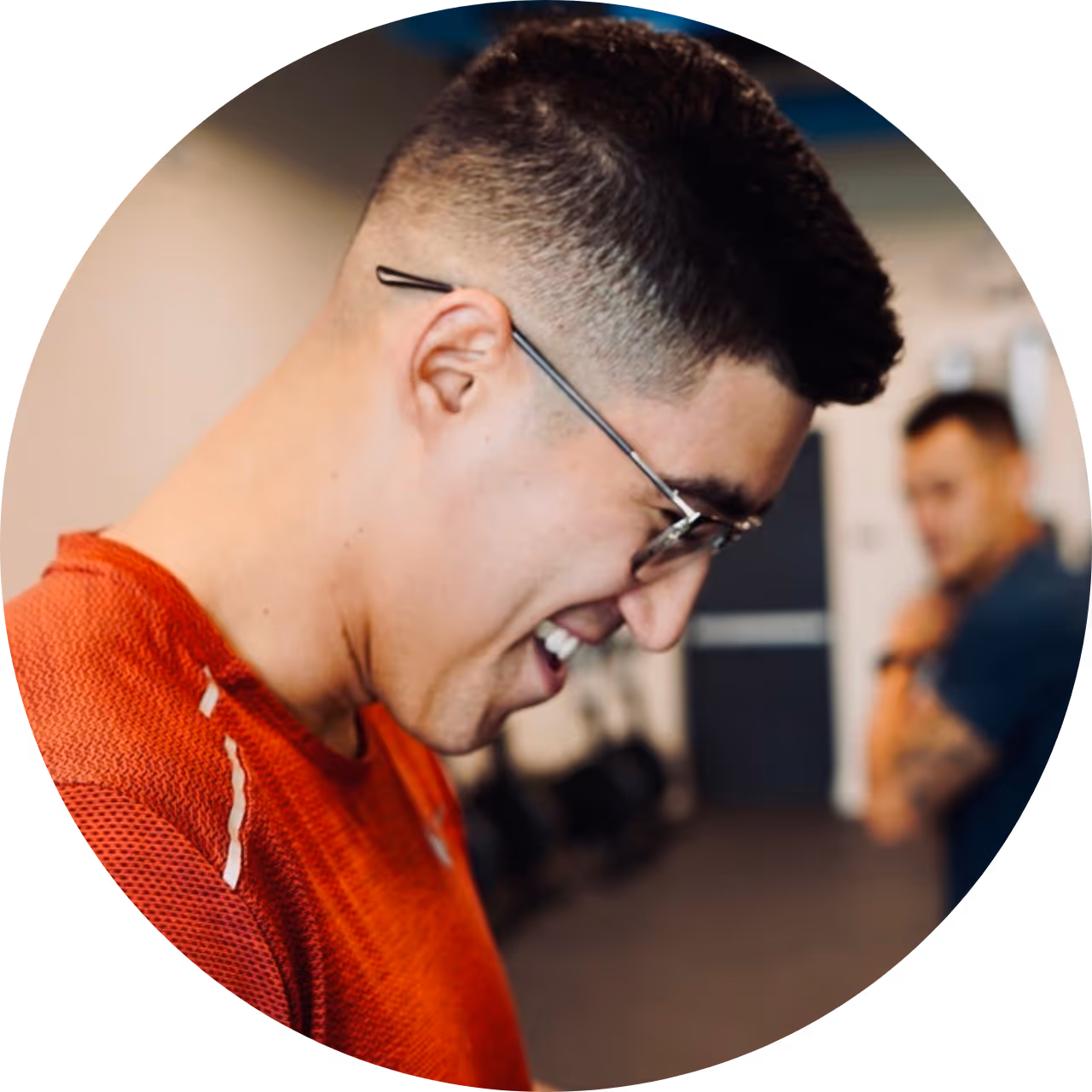 A proof3 member, Jarryd, smiling big in the proof3 salt river gym with proof3 coach, Carl, standing in the background